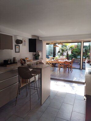 A modern kitchen with a central island, bar stools, and a dining area with a table and chairs. - Charming townhouse for 4 people near the Blavet River (Pontivy)