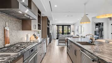 A modern kitchen with a central island, stainless steel appliances, and a herringbone-patterned backsplash.
