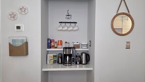 A kitchenette with a coffee maker, pots, a shelf with coffee pods, and a guest book. - First Floor • Closest to Private Beach • Newly Renovated • Pools & Amenities (Hilton Head Island)