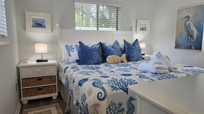 A bedroom with a bed, nightstands, a lamp, a plush toy, and artwork on the walls. - First Floor • Closest to Private Beach • Newly Renovated • Pools & Amenities (Hilton Head Island)