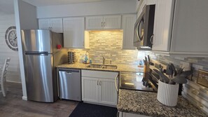 Eine moderne Küche mit Edelstahlgeräten, einer Arbeitsplatte aus Granit und einer Spritzschutzwand mit Mosaikfliesen.