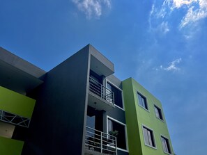 A modern building with a flat roof, large windows, and a balcony with a metal railing. - Spacious 3-bedroom apartment with Office in San Salvador. (San Salvador)