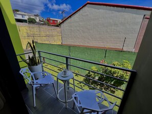 A balcony with two white chairs, a small table, and a potted plant. - Spacious 3-bedroom apartment with Office in San Salvador. (San Salvador)