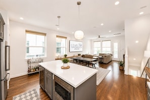 A spacious kitchen with a central island, a dining area, and a living room with a sofa.