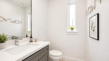 Un baño moderno con un lavabo blanco, un inodoro y una ventana.
