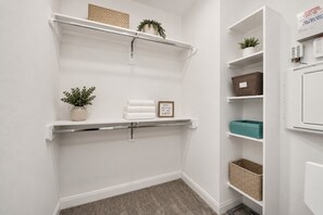 A white closet with shelves, a towel rack, and storage boxes.