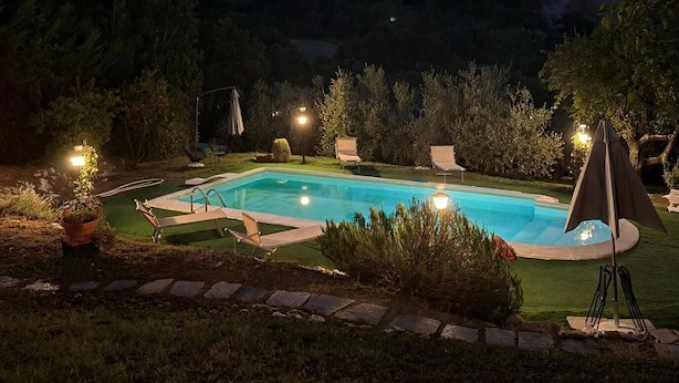 A swimming pool at night with surrounding lounge chairs and a starry sky. - Casale Santilli (Agnone)