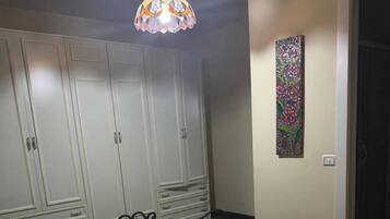 Ein Schlafzimmer mit einem Bett, einem Kleiderschrank, einer Pendelleuchte und einem Wandbild.