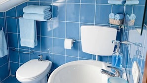 A bathroom with a toilet, sink, and blue tiled walls. - Casale Santilli (Agnone)