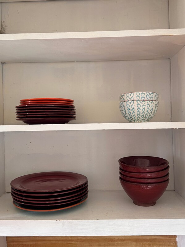 A shelf with stacked plates and a patterned bowl.