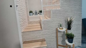 A staircase with a white brick wall and a wooden floor leading to a landing with potted plants. - Furnished and fully equipped Piazza Plebiscito House on Via Toledo in downtown Naples (Napoli)
