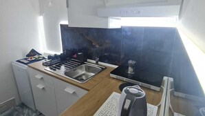 A compact kitchen with a sink, stove, and a coffee maker on a small table. - Furnished and fully equipped Piazza Plebiscito House on Via Toledo in downtown Naples (Napoli)