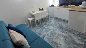 A compact living space with a sofa, a small dining table, and a kitchenette area. - Furnished and fully equipped Piazza Plebiscito House on Via Toledo in downtown Naples (Napoli)