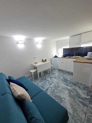 A compact living space with a sofa, a small dining table, and a kitchenette area. - Furnished and fully equipped Piazza Plebiscito House on Via Toledo in downtown Naples (Napoli)