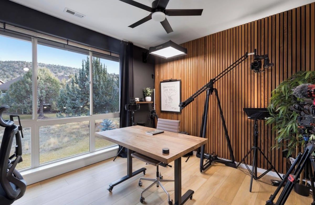 Une chambre moderne dotée d’une grande fenêtre, d’un ventilateur de plafond et d’un mur en bois.