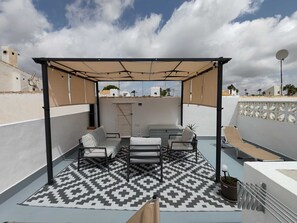 A rooftop terrace with a covered seating area, a patterned floor, and a view of the surrounding neighborhood. - Tranquil oasis in Costa Blanca (VC)