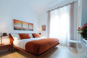 A modern bedroom with a large bed, bedside lamps, a nightstand, and a window with curtains. - 3-Bedroom, 3-Bathroom Premium Vatican Apartment - Free Luggage Storage Included (Roma)