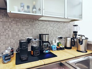 Een keuken met een koffiezetapparaat, een blender en een waterkoker op het aanrecht.