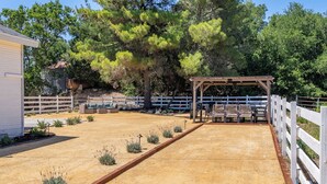 Ein eingezäunter Außenbereich mit einer Pergola, Sitzgelegenheiten und einem Gebäude im Hintergrund.