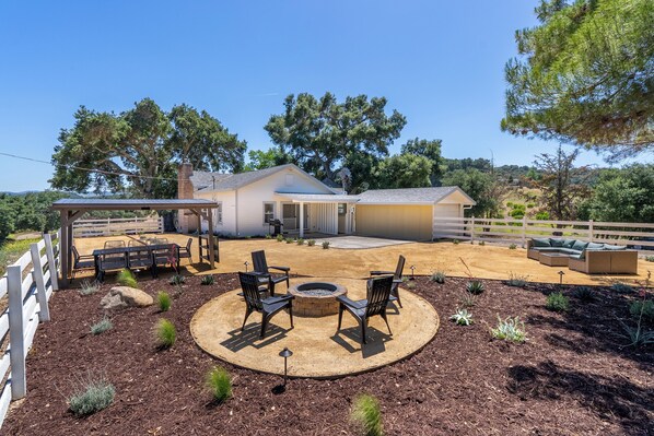 A house with a covered patio area, outdoor seating, and a fire pit.