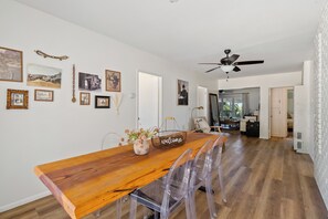 A dining area with a wooden table, clear chairs, and a 'welcome' sign.