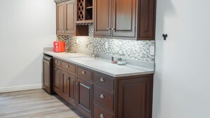 Uma cozinha com armários de madeira, bancada e painel de azulejos.