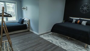 Quarto com duas camas, uma janela, um relógio na parede e uma escada de madeira.