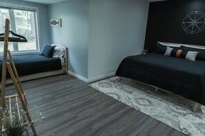 Ein Schlafzimmer mit zwei Betten, einem Fenster, einer Wanduhr und einer Holzleiter.