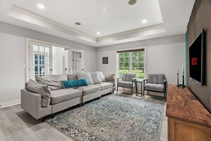 Un salon moderne avec un canapé gris, un tapis à motifs et un téléviseur fixé au mur.