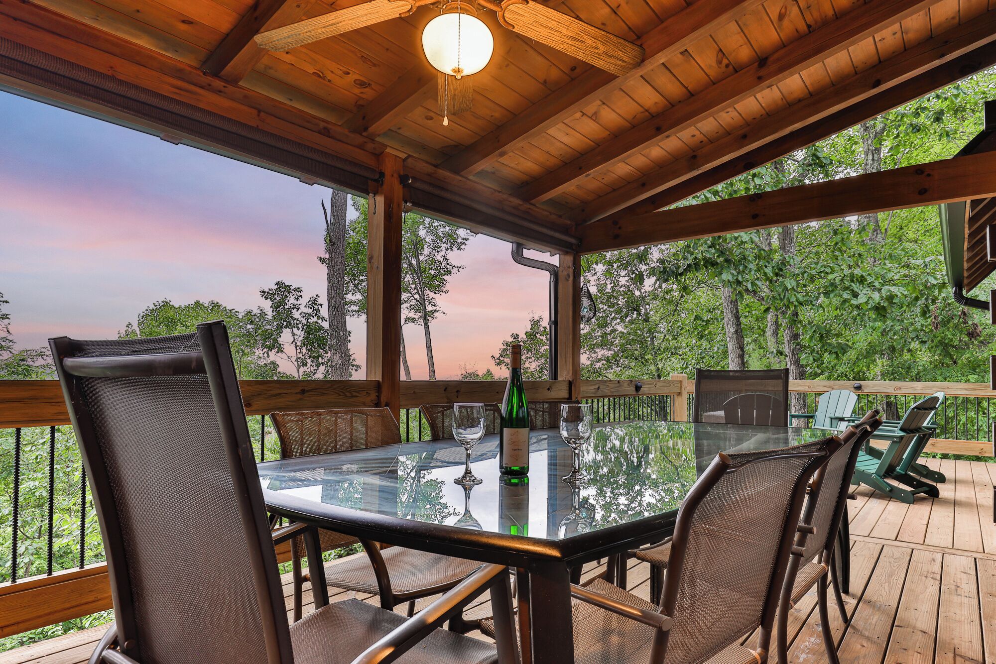 Un espace extérieur abrité, aménagé pour les repas, avec une table en verre, des chaises en métal et un plafond en bois.