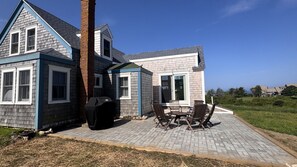 A two-story house with a patio area featuring a grill and outdoor furniture. - 4 BR/2 BA Charmer! Sunset and Ocean Views, Steps to the Beach! (New Shoreham)