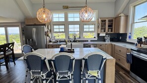 A kitchen with a large island, wooden cabinets, and a view of the outdoors. - 4 BR/2 BA Charmer! Sunset and Ocean Views, Steps to the Beach! (New Shoreham)