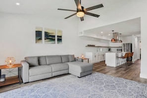 A modern living room with a grey sectional sofa, a wooden coffee table, and a patterned rug. - Spacious 3BR/2BA Retreat - Walk to town (St. Augustine)