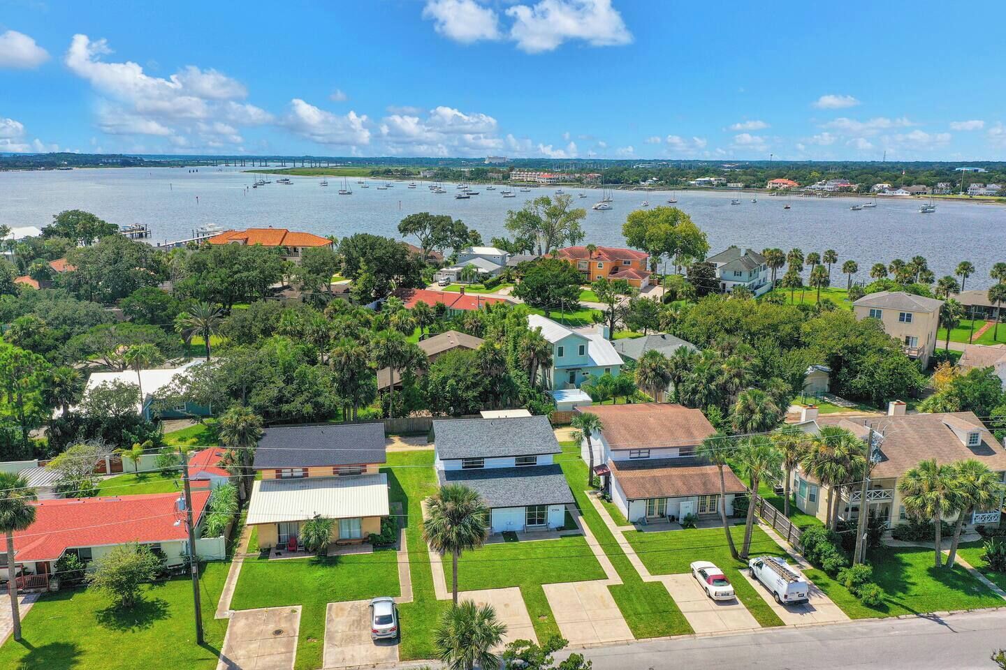 A residential area with houses, a clear sky, and a body of water in the background.