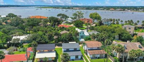 A residential area with houses, a clear sky, and a body of water in the background.