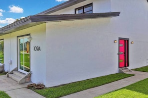 A modern building with a white exterior, a red door, and a number '109A' on the wall. - Spacious 3BR/2BA Retreat - Walk to town (St. Augustine)