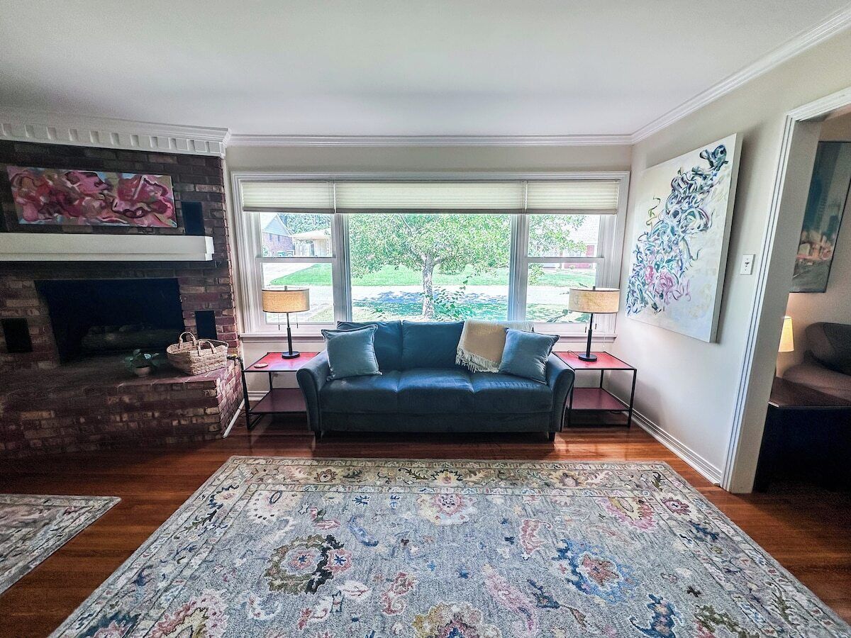 A living room with a fireplace, a sofa, a rug, and artwork on the walls.