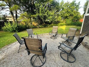 Terrassenmöbel im Freien, bestehend aus Tisch und Stühlen, auf einer Kiesfläche.