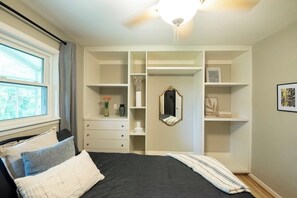 Een slaapkamer met een bed, een kledingkast, een spiegel en een raam.