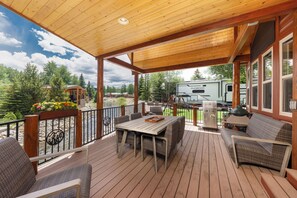 A covered deck with outdoor furniture, a grill, and a view of a lake and forest. - Magical Breckenridge Chalet on the Swan River close to clubhouse (Breckenridge)