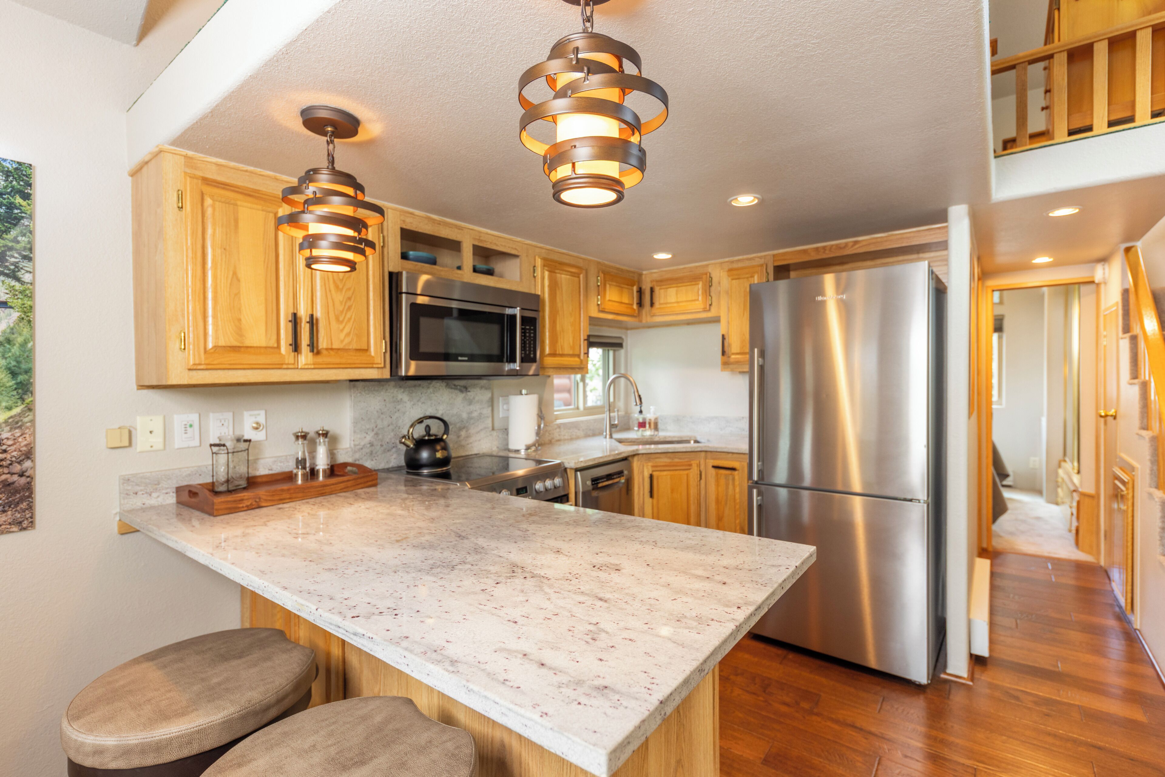 A modern kitchen with wooden cabinets, stainless steel appliances, and a marble countertop.