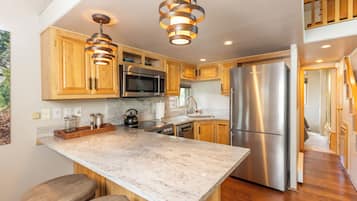 A modern kitchen with wooden cabinets, stainless steel appliances, and a marble countertop.