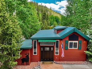 A log cabin with a green roof, a deer sculpture, and an American flag. - Magical Breckenridge Chalet on the Swan River close to clubhouse (Breckenridge)