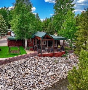 A cabin with a porch, a swing, and a gravel path leading to a wooden deck.
