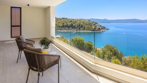 A balcony with a view of a coastal landscape, a table with a plant, and two chairs. - Stunning home in Duba (Duba)