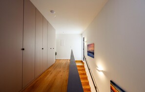 Ein Korridor mit Holzboden, weißen Wänden und einer Treppe mit Handlauf.