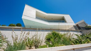 A modern building with a unique angular design, featuring a large overhang and a balcony. - Stunning home in Duba (Duba)