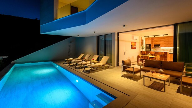 A modern outdoor pool area with lounge chairs and a dining area with a table and chairs. - Stunning home in Duba (Duba)