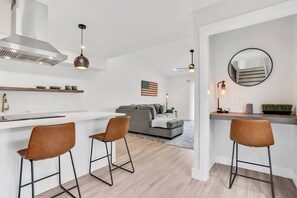 A modern kitchen with a white countertop, two bar stools, and a built-in stove. - Welcoming 2BR/2BA Get Away-Walk to St. Aug (St. Augustine)