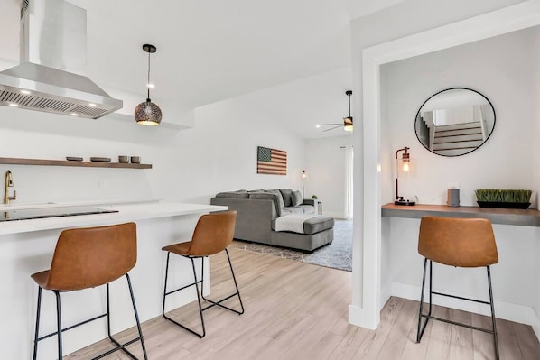 A modern kitchen with a white countertop, two bar stools, and a built-in stove. - Welcoming 2BR/2BA Get Away-Walk to St. Aug (St. Augustine)